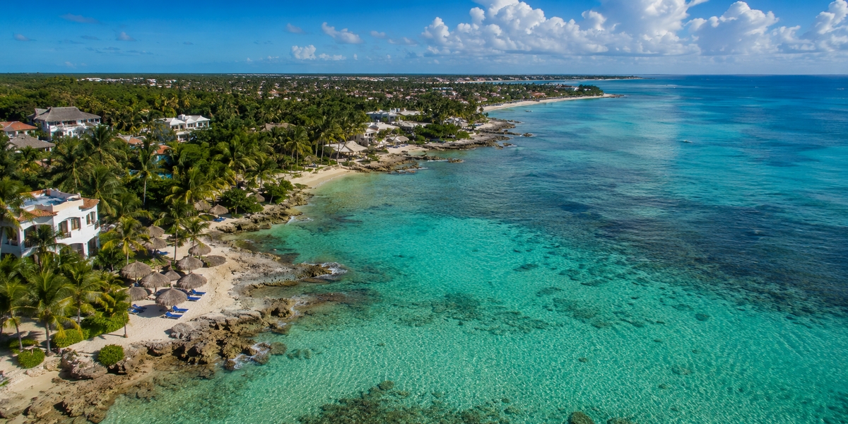Calm Half Moon Bay cove near Akumal with low-rise condos and a rocky reef entry